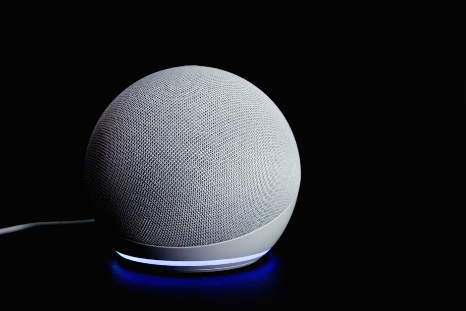 Amazon Echo Dot 5th-generation smart speaker on a wooden desk with the LED ring lit