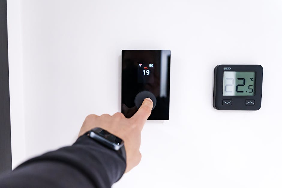 Close-up of a hand adjusting a sleek, modern smart thermostat mounted on a home wall